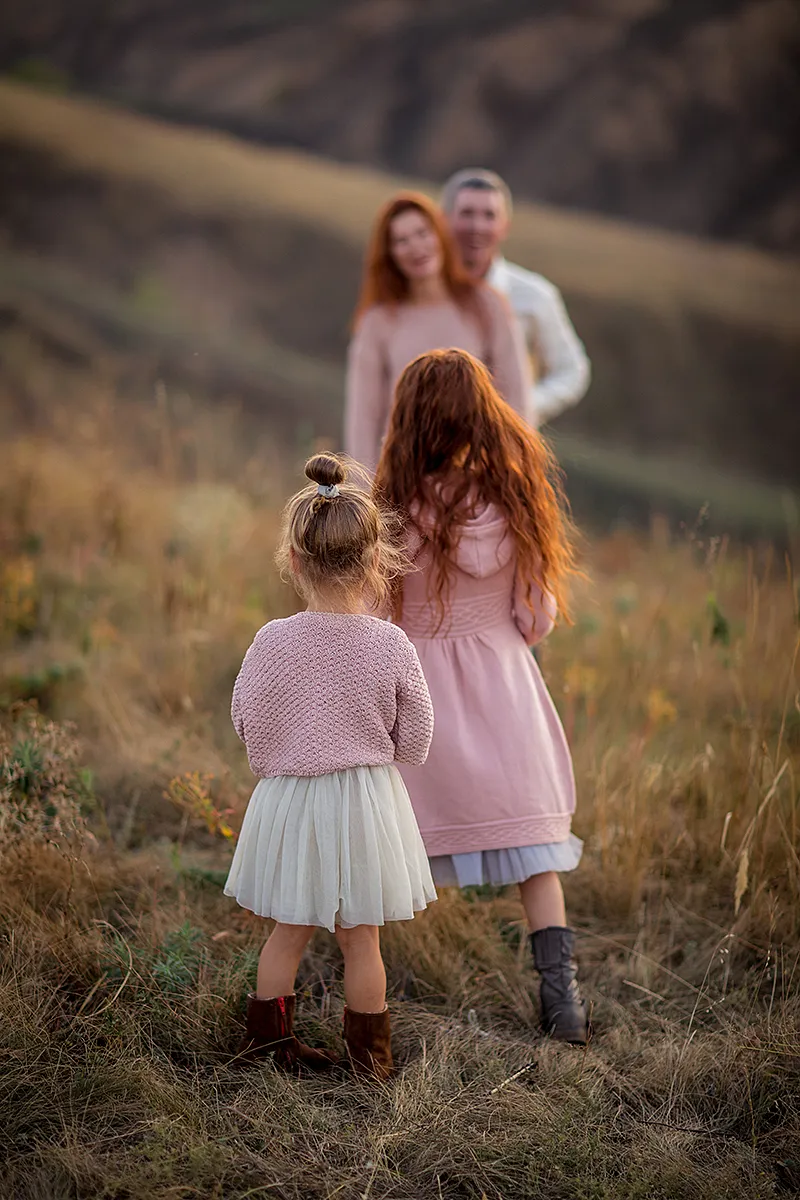 Parents and two daughters walking through tall autumn grass