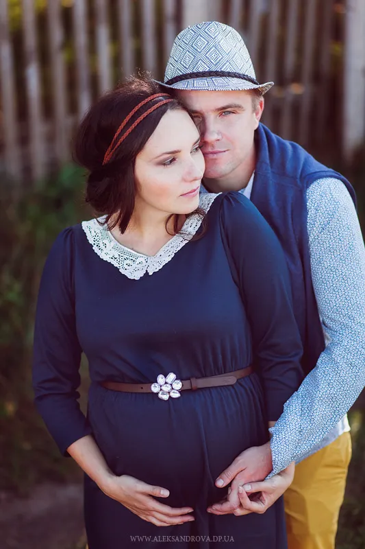 Expectant couple embracing in a garden, hands on the bump