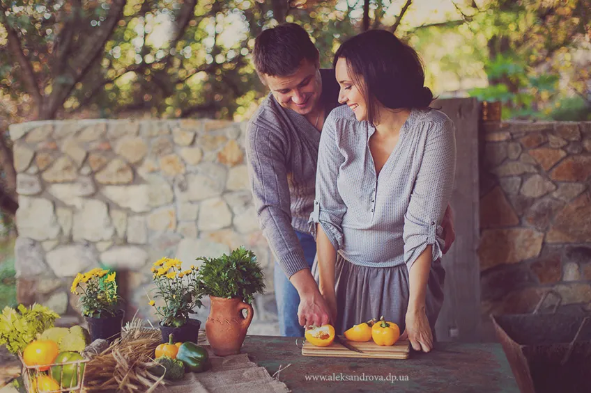 Expectant couple preparing vegetables together at a rustic table