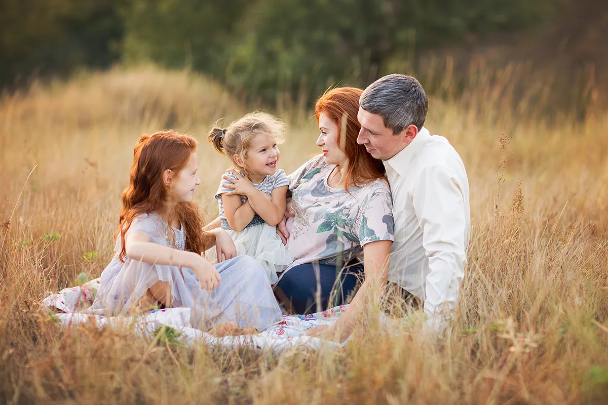 Family relaxing together on a blanket in tall grass