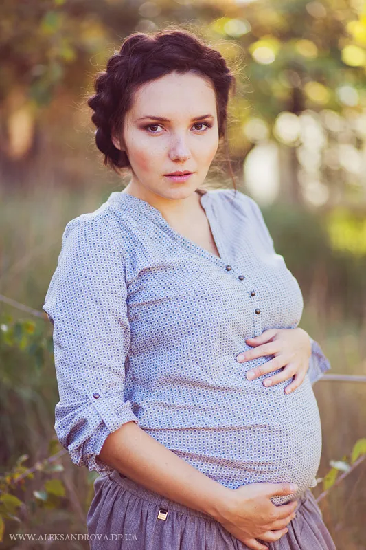 Pregnant woman holding her bump in a sunlit garden