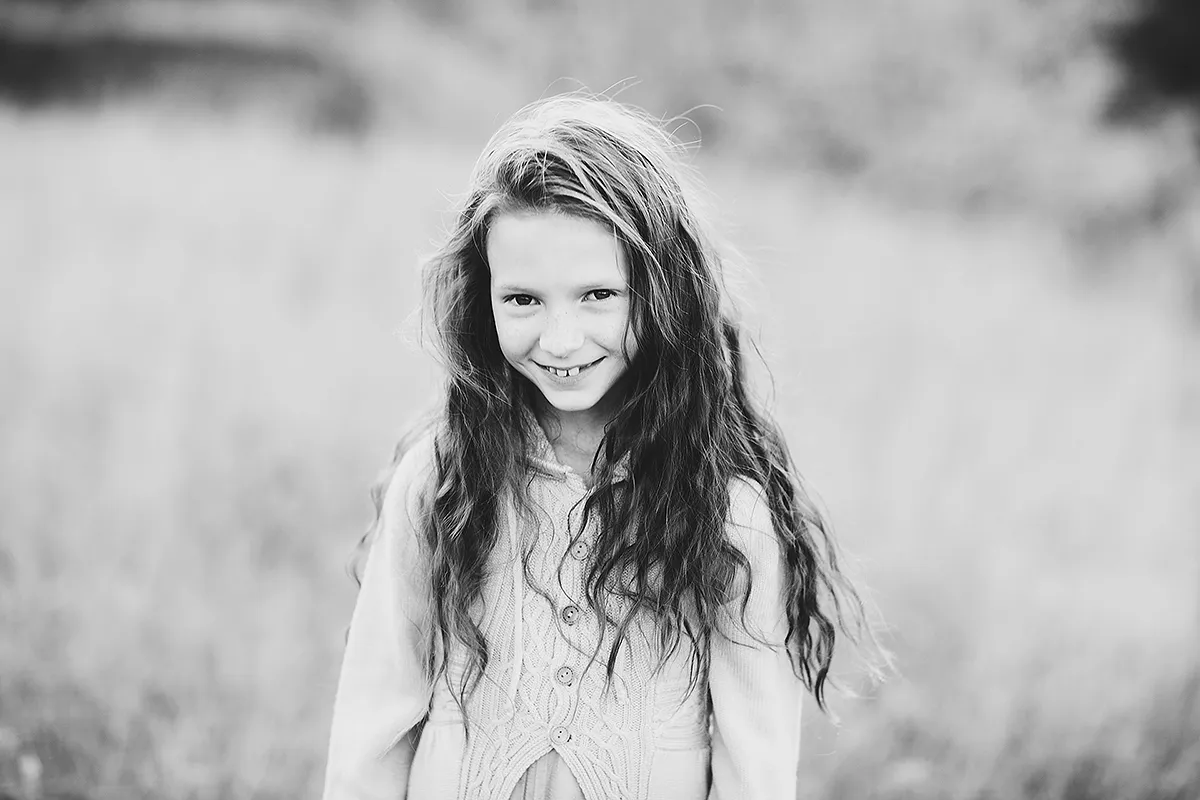 Black and white portrait of a smiling girl with long hair outdoors