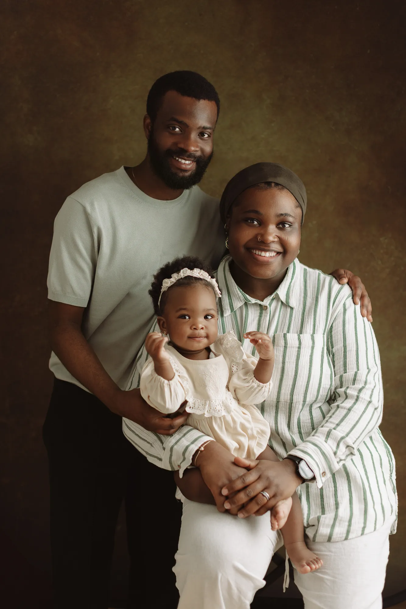 The birthday girl with her mum and dad against a brown painted backdrop