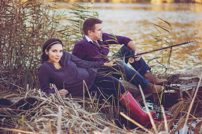 Expectant couple relaxing on a riverbank