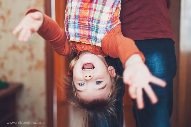 Laughing boy held upside down by his dad at home