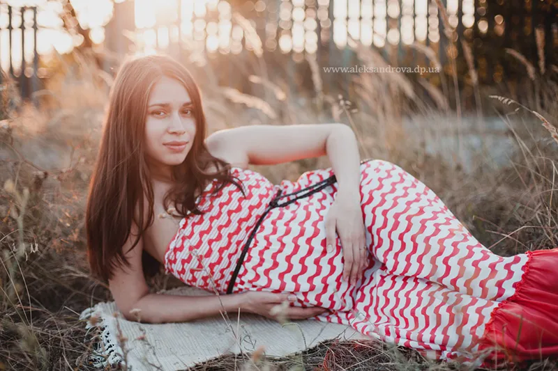 Pregnant woman reclining in the grass in a chevron maxi dress