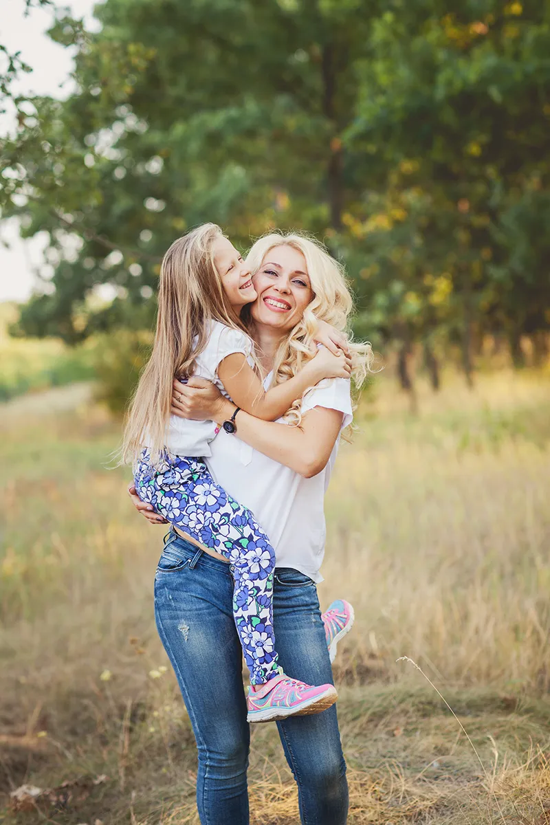 Mother lifting her laughing daughter in a sunny park