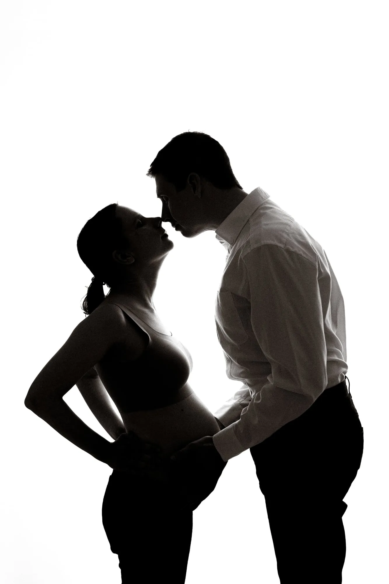 Black and white silhouette of an expectant couple about to kiss