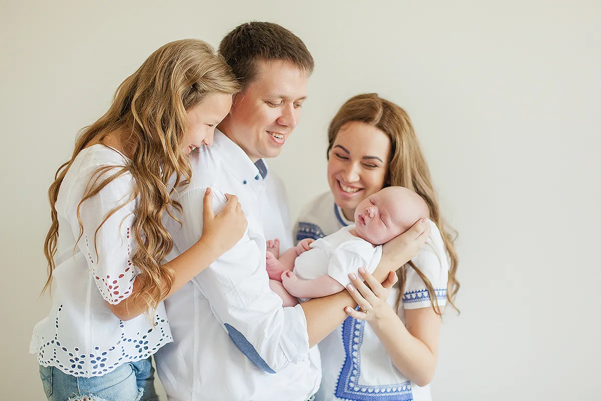 Parents and daughter cuddling a newborn baby at home
