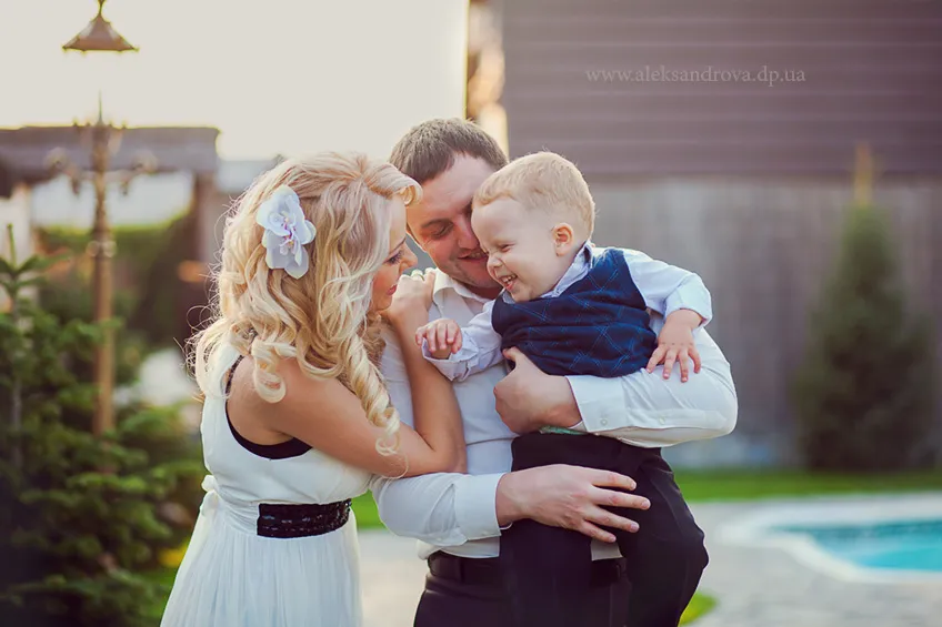 Parents kissing their toddler son in a garden