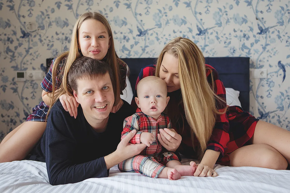 Family with a baby lying together on a bed at home